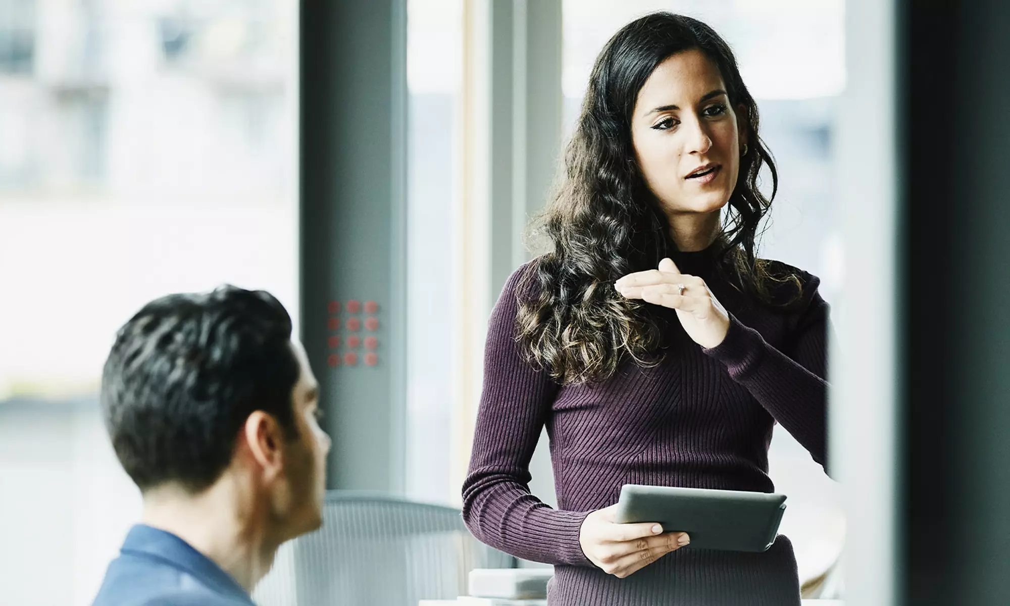 女性手持平板電腦與同事交談