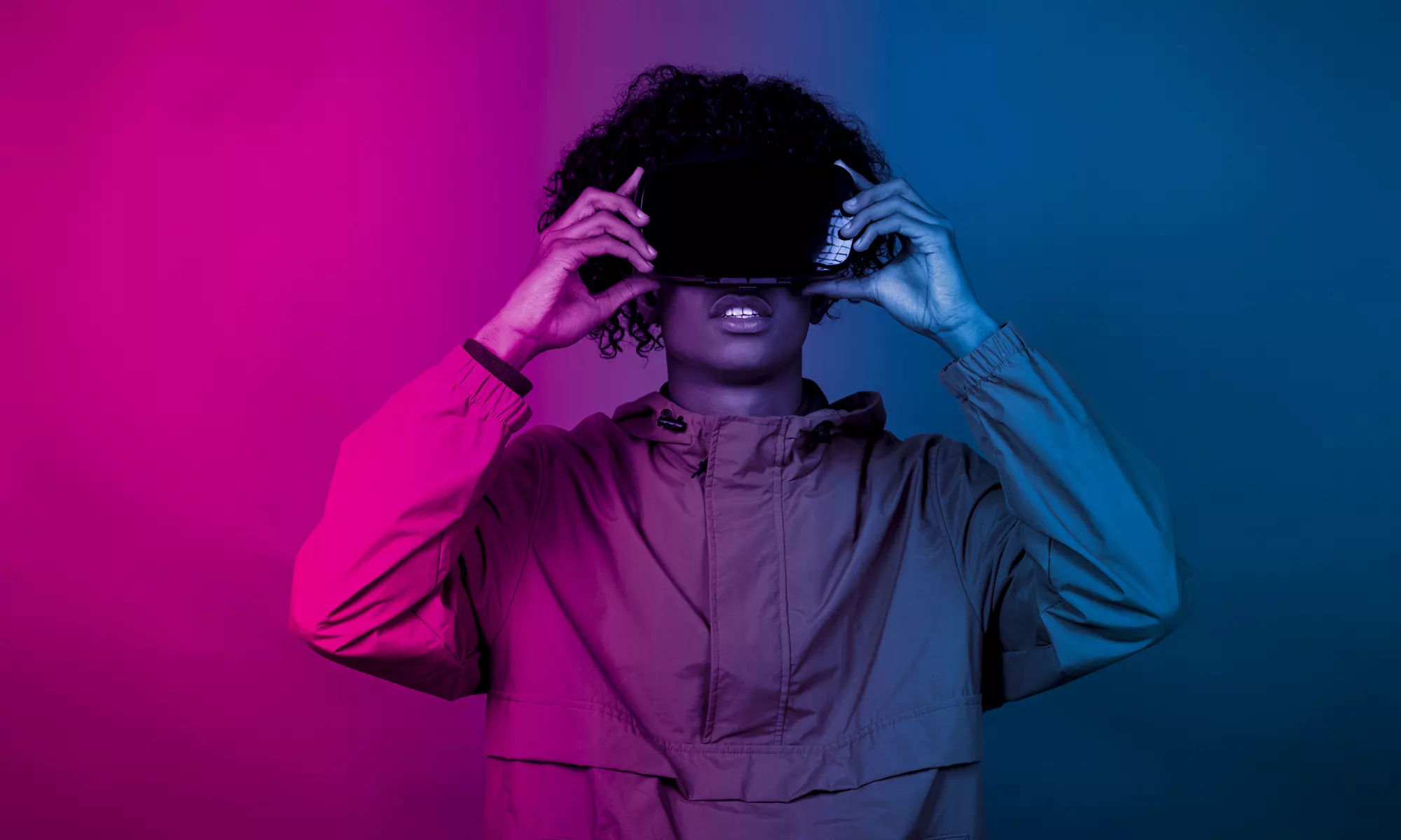 A young African male with VR glasses standing under the blue and purple lights