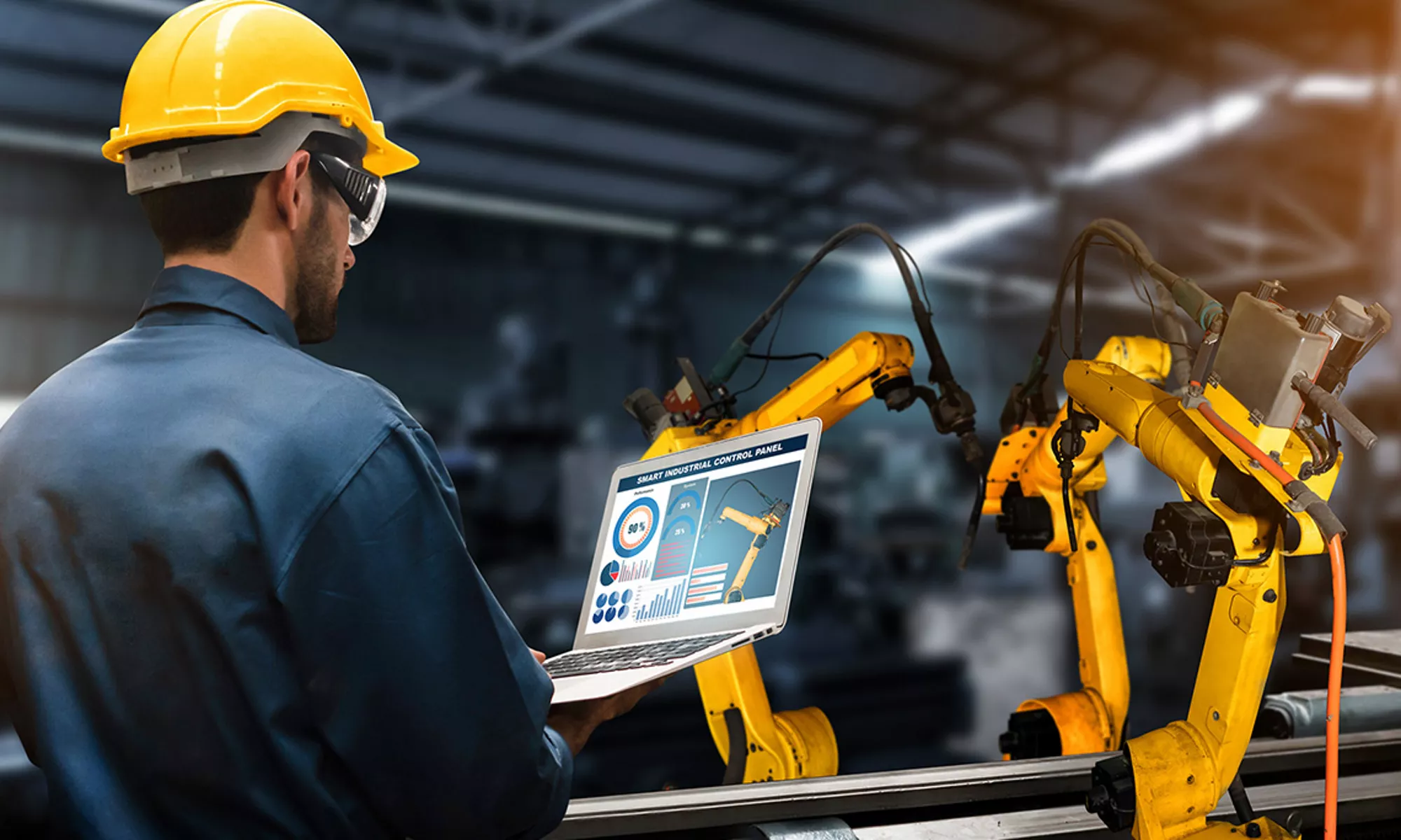 戴著黃色安全帽的男子透過數位螢幕控制機器人設備